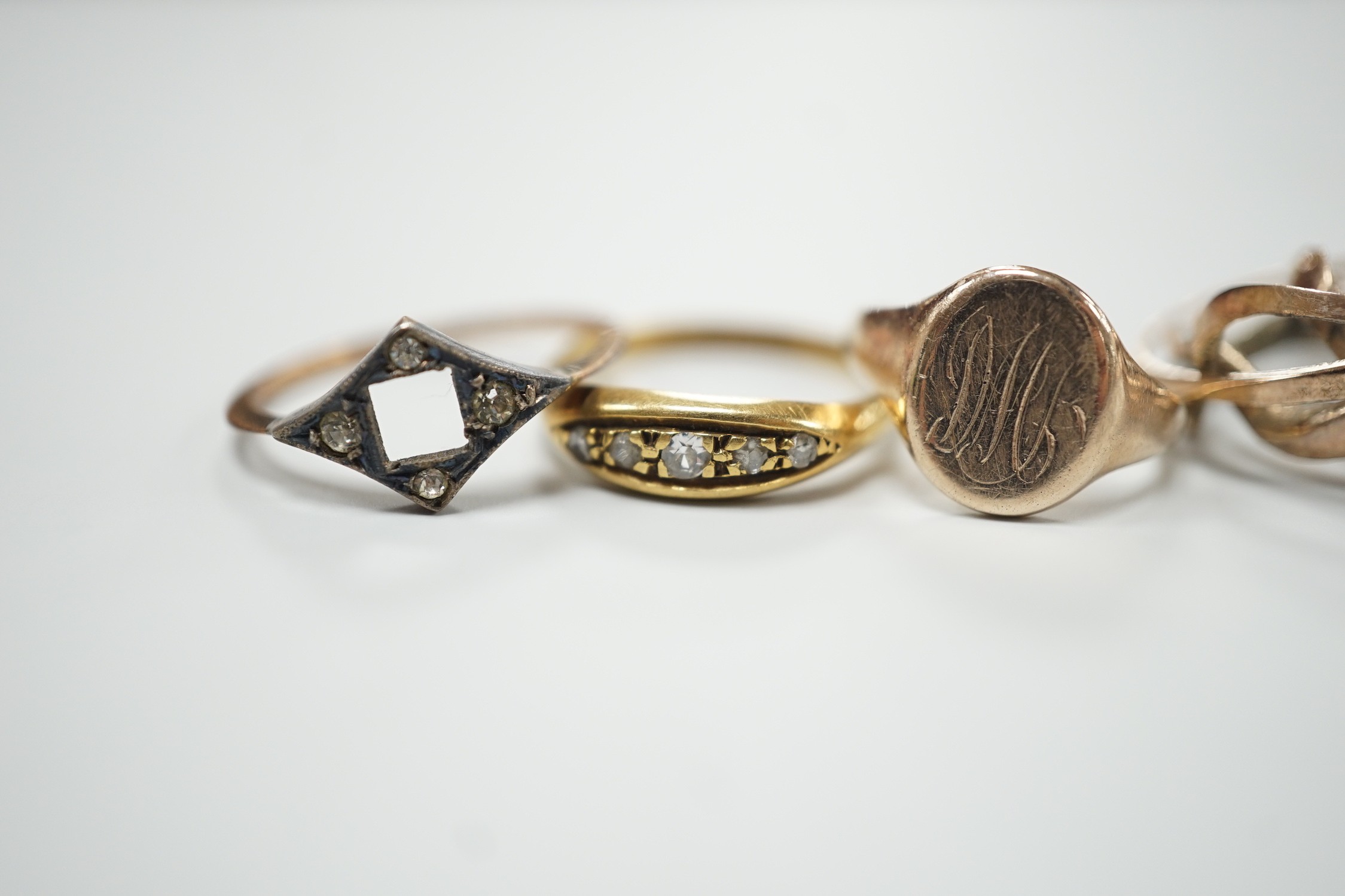 An 18ct gold and five stone diamond chip set ring, size L, gross 2.7 grams, two 9ct rings including small signet, gross 3.4 grams and a yellow metal puzzle ring.